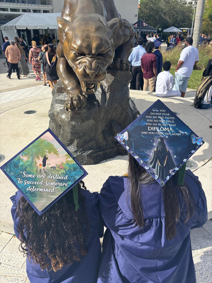 Two graduates wearing Pooh and Diploma quote caps at FIU panther