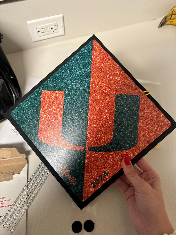 Hands holding Miami U split glitter topper