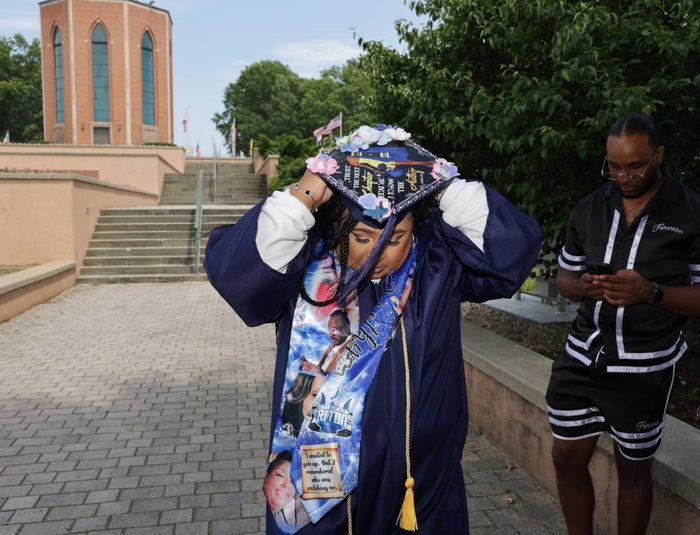 Graduate adjusting photo collage cap on steps