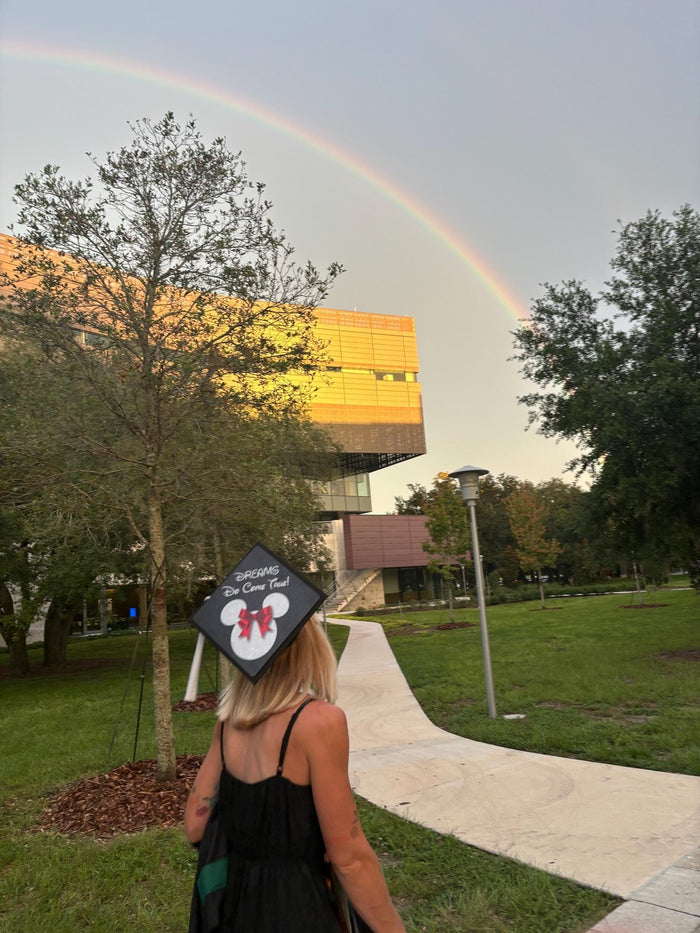 Woman wearing Minnie Dreams Do Come True cap under rainbow