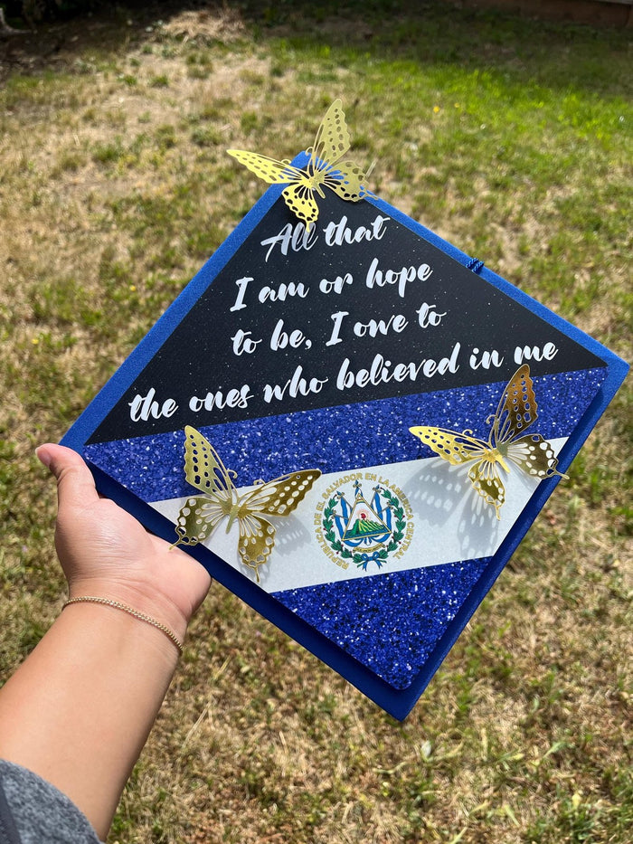 Hand holding El Salvador butterfly cap over grass