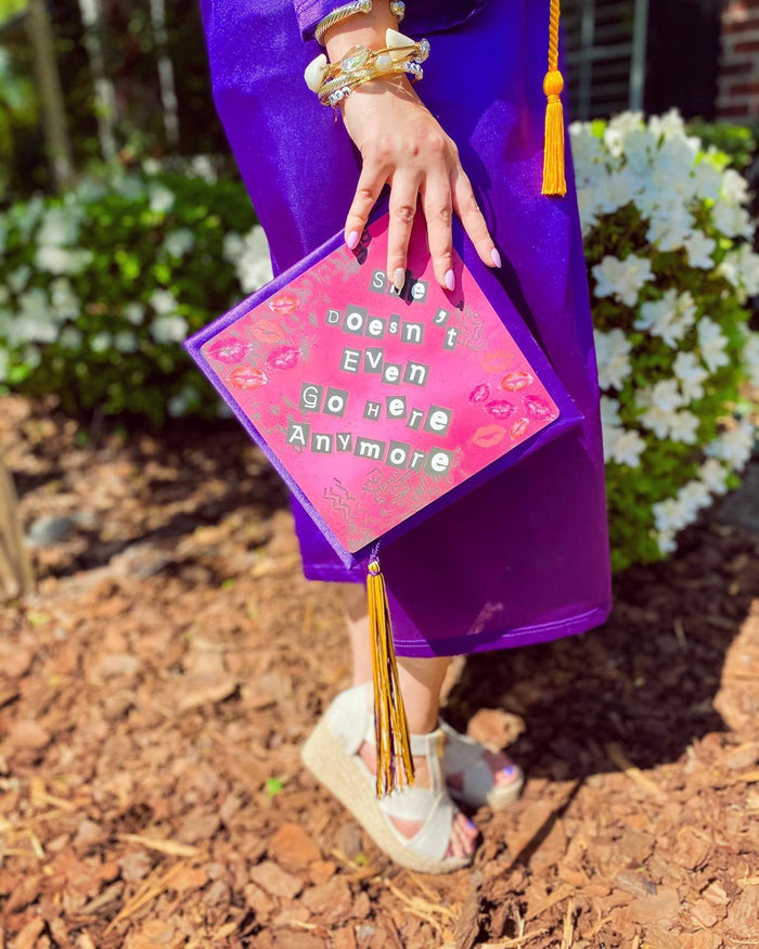 Graduate holding Mean Girls pink cap at side