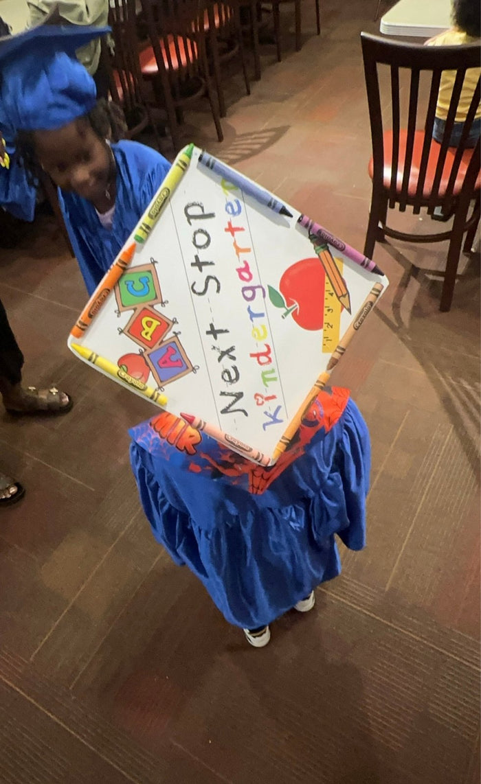 Child holding Next Stop Kindergarten cap