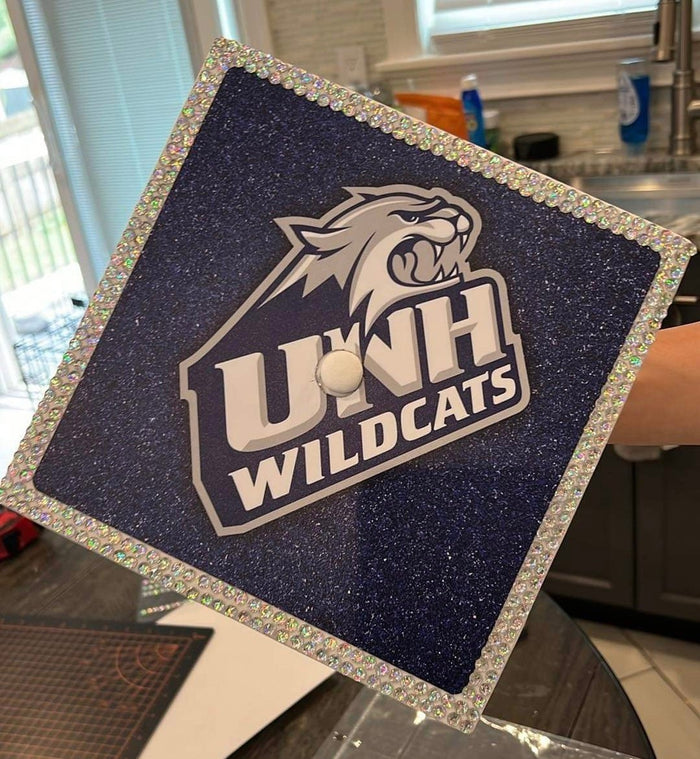 Arm holding UNH Wildcats glitter cap