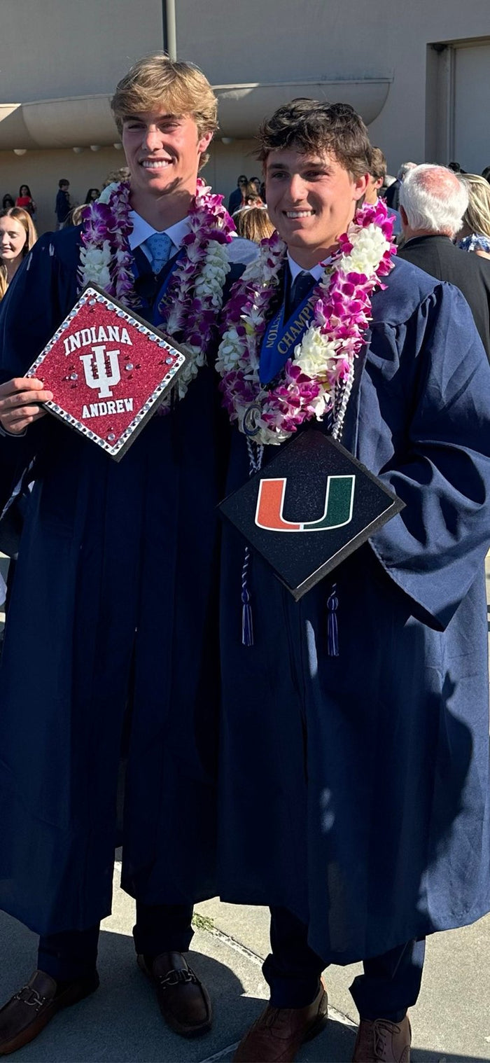 Two graduates holding Indiana and Miami toppers