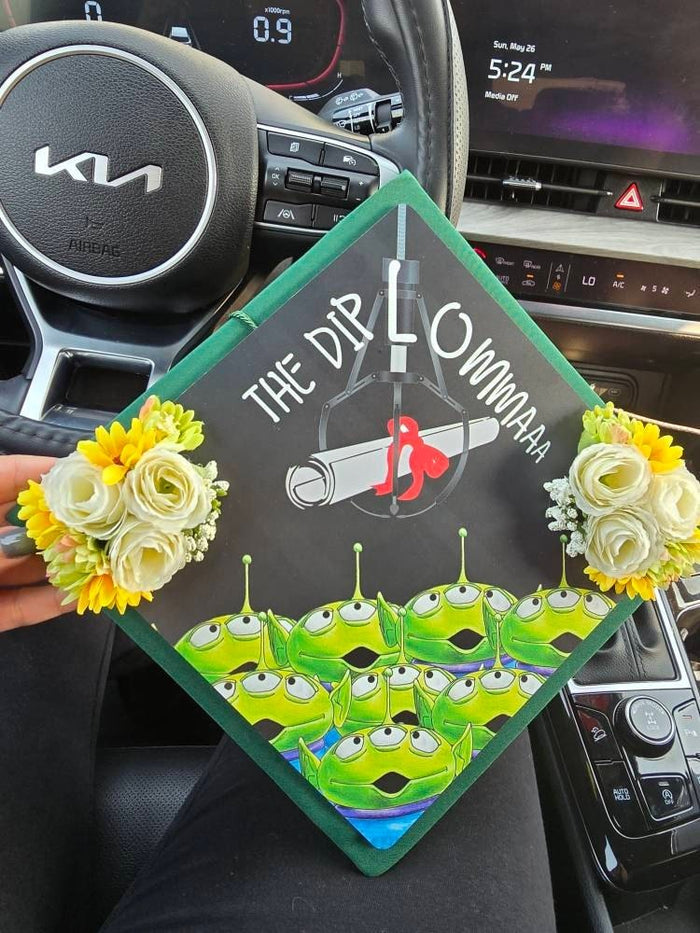 Hand holding Toy Story aliens floral topper in car