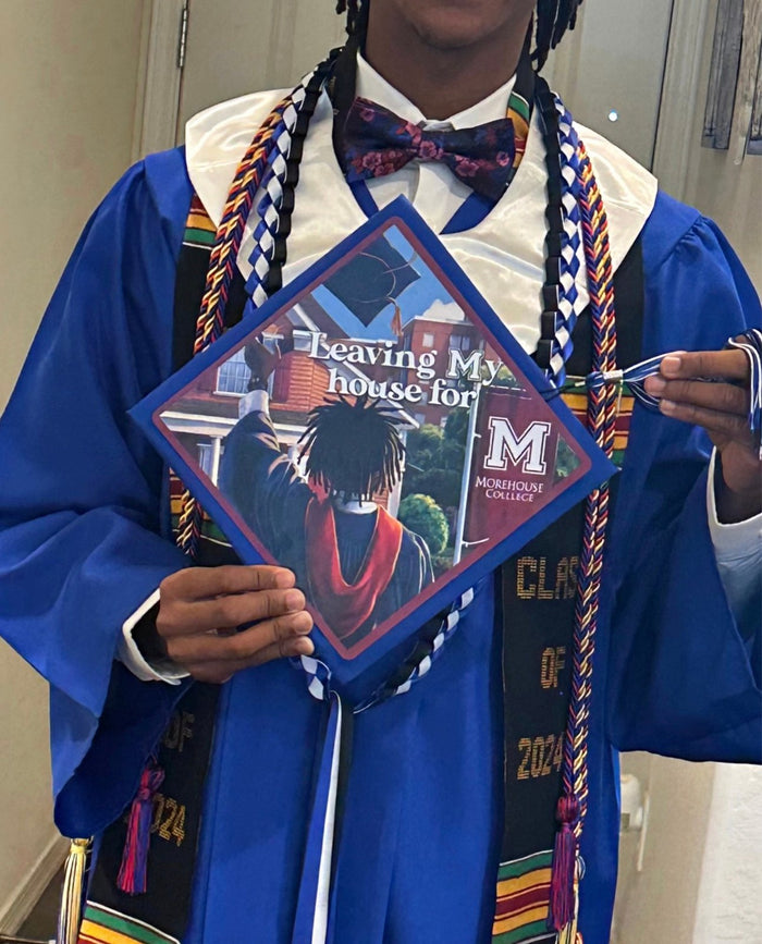 Graduate holding Leaving My House For Morehouse cap