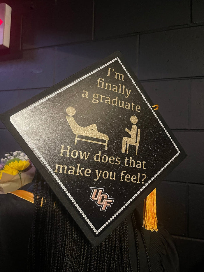 Graduate wearing UCF therapy How Does That Make You Feel cap