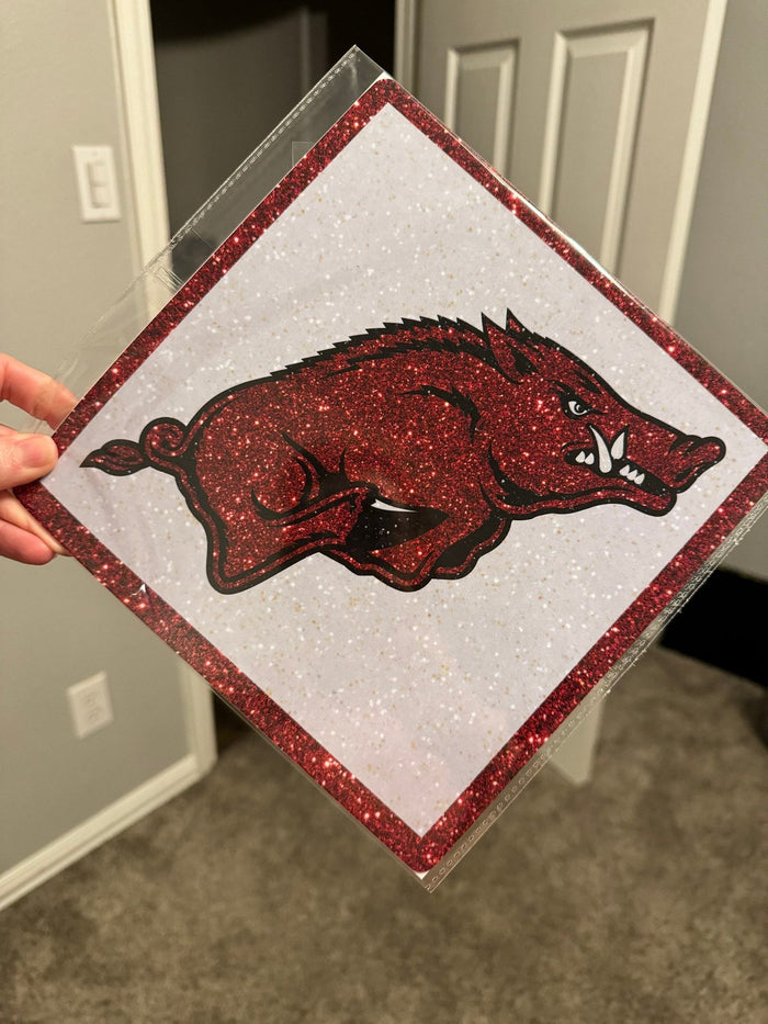 Hand holding Arkansas Razorback glitter topper