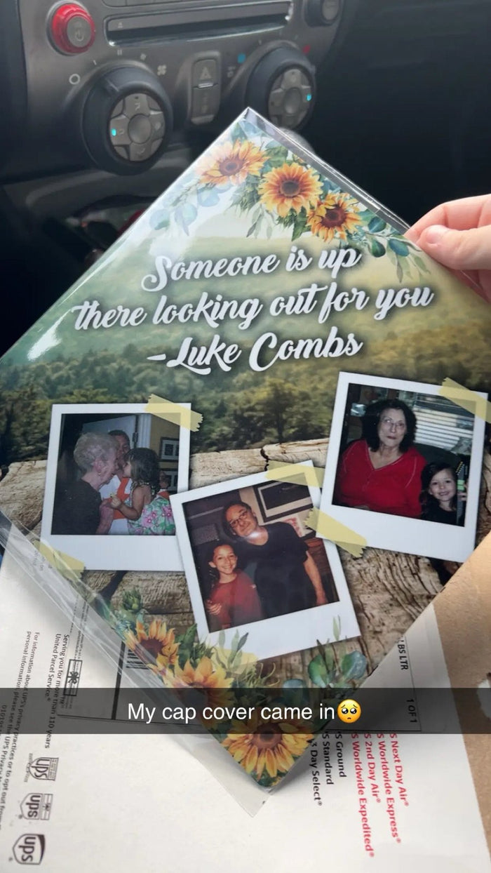 Hand holding Luke Combs memorial polaroid topper in car
