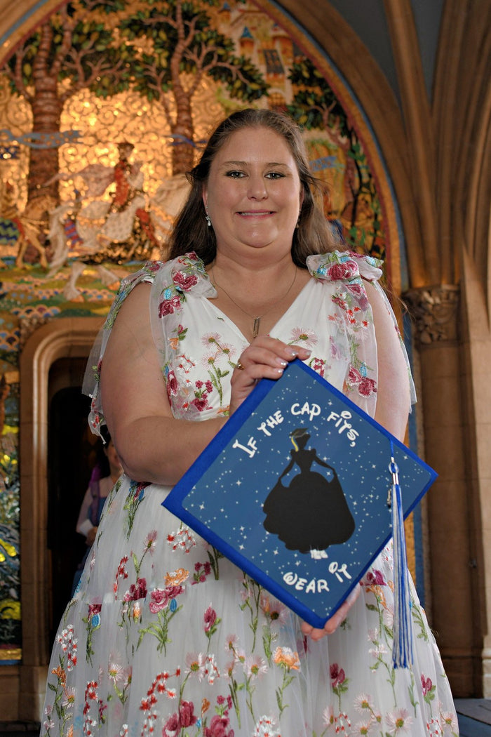Woman holding If The Cap Fits Cinderella cap in church