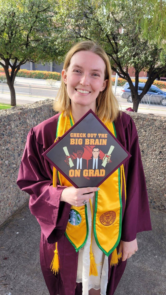Graduate holding Big Brain On Grad topper