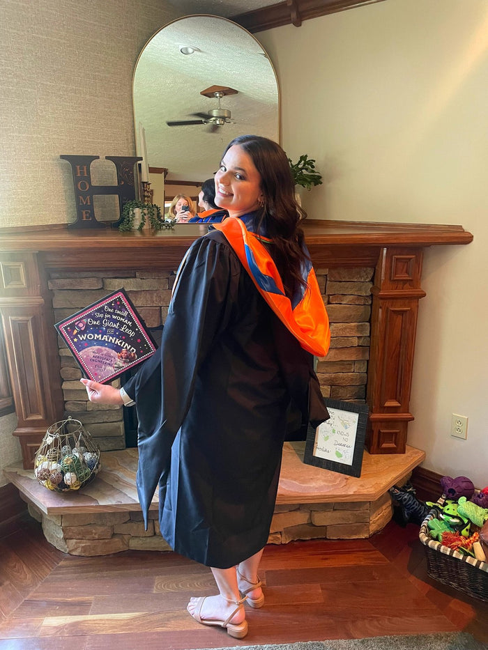 Graduate holding One Giant Leap For Womankind aerospace cap