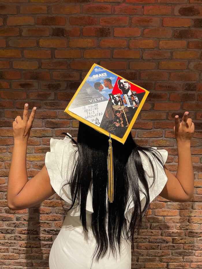 Woman wearing photo collage cap at brick wall