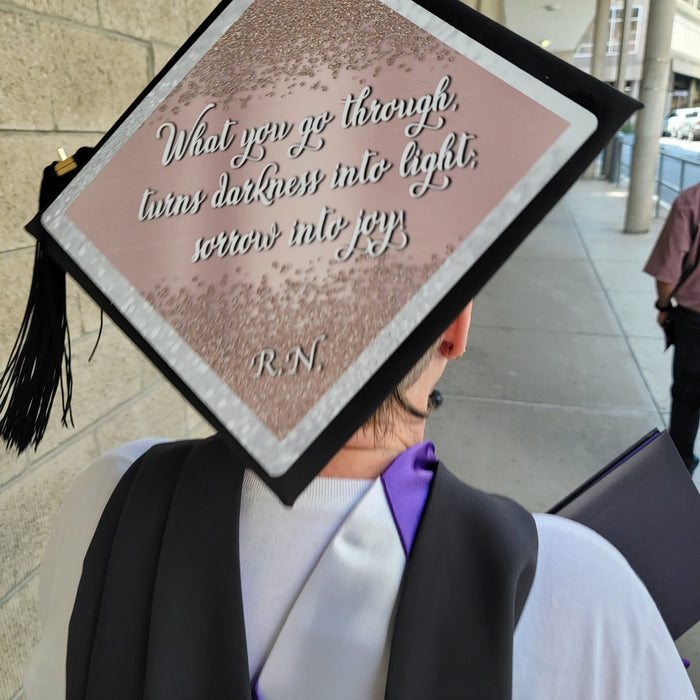 Graduate wearing RN darkness into light cap