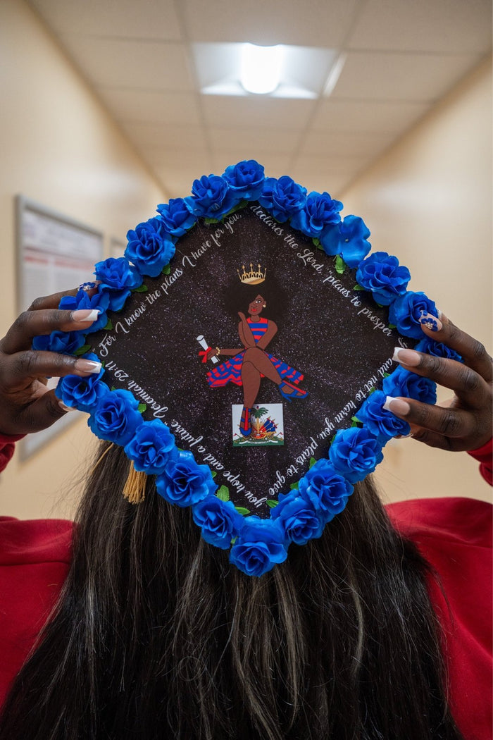 Graduate holding blue rose crown topper over head