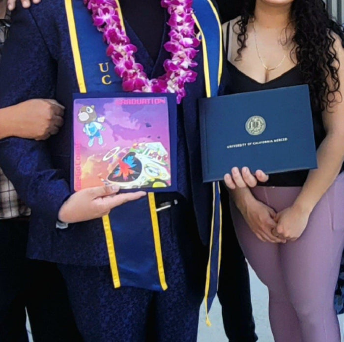 Graduate holding Kanye topper and diploma