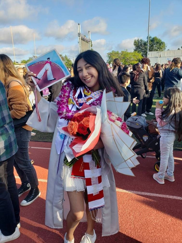Graduate holding Harry Styles Out Of Style cap with roses