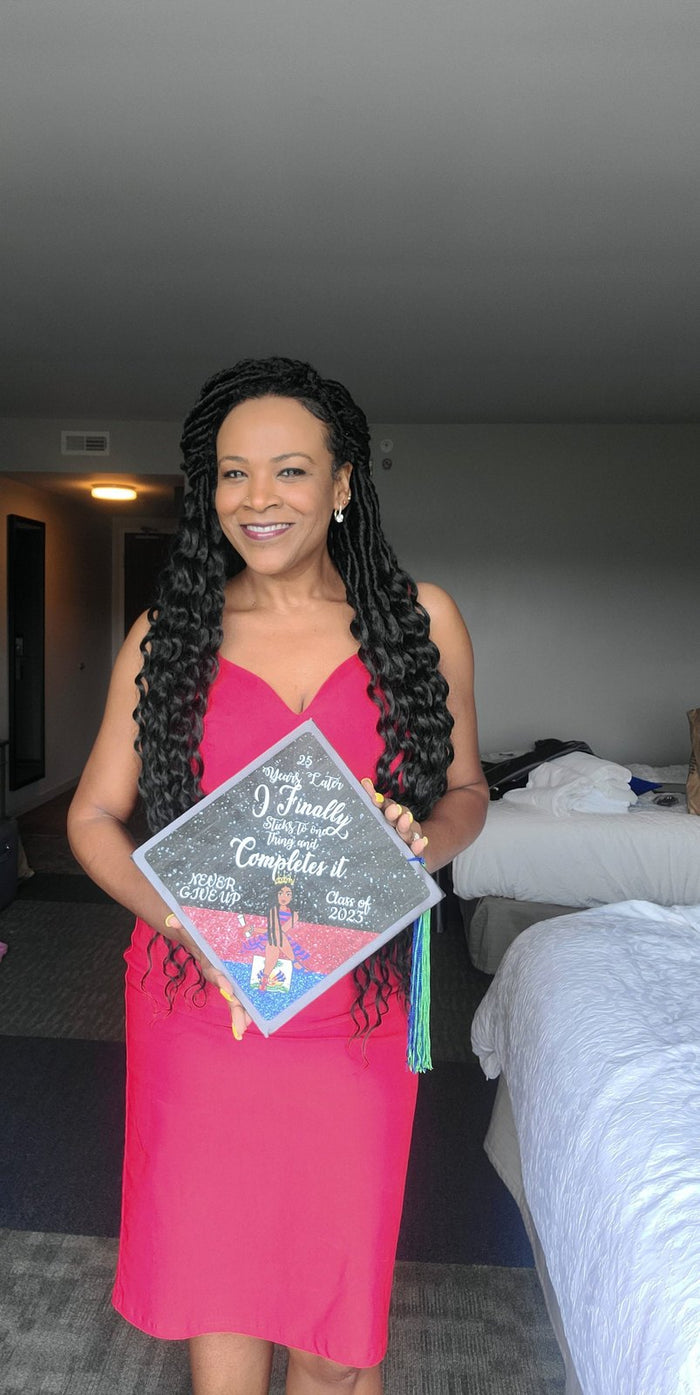 Woman holding I Finally Completed topper in hotel room