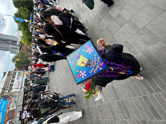 Graduate wearing SpongeBob bachelors degree cap in crowd