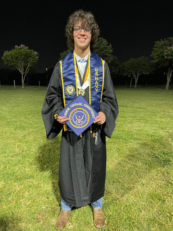 Graduate holding Navy seal cap at night