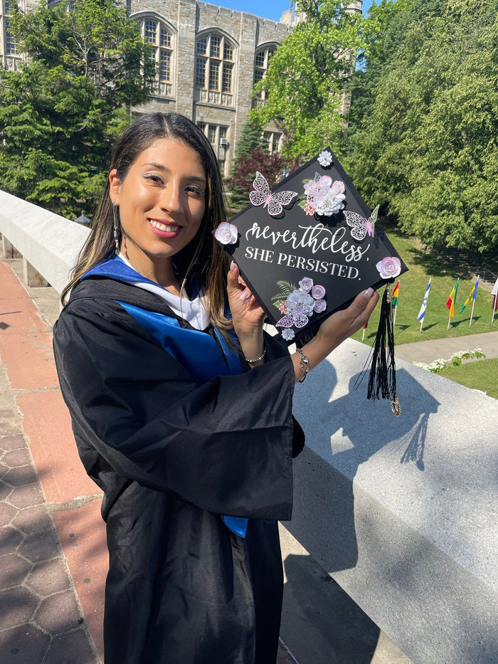 Graduate holding Nevertheless She Persisted butterfly cap
